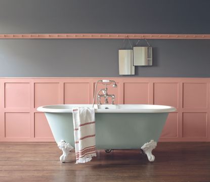Coral painted bathroom with paneling and green tub