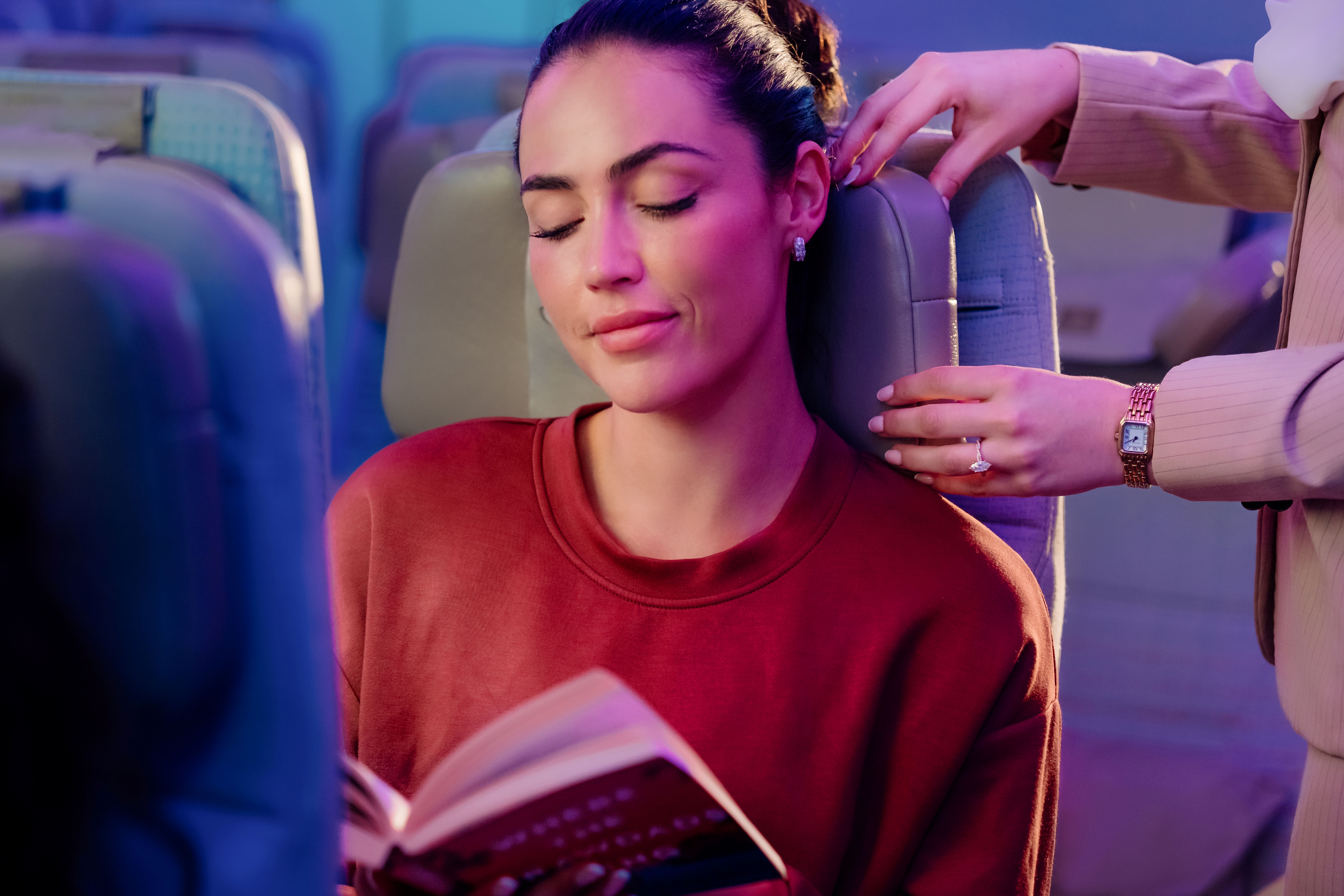 A female passenger relaxing in an Emirates Economy Class seat while using the world's first U-Dream headrest