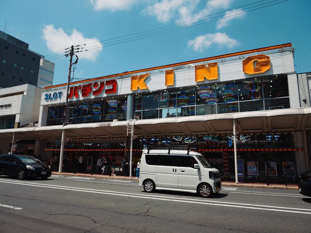 Pachinko and slot arcade storefront under a blue sky.
