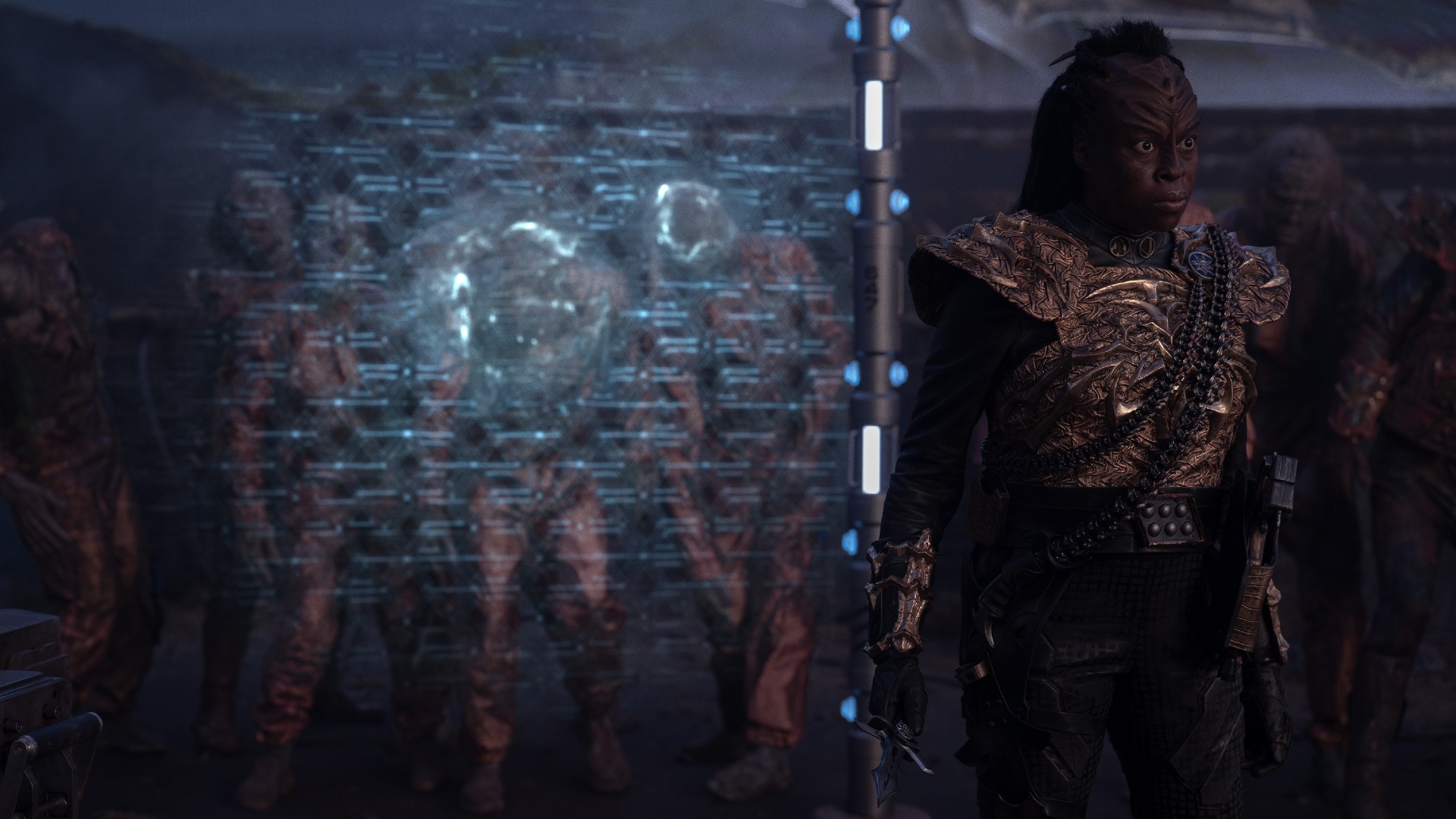 An angry female Klingon is holding a dagger. Behind her zombies are held off by a forcefield. Christine Horn as Bytha in season 3 , Episode 3 of Strange New Worlds streaming on Paramount+.
