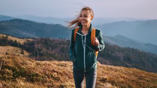 Woman outdoors in nature walking with a backpack on smiling
