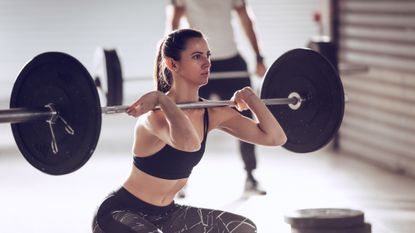 Woman performing loaded front squat with a barbell