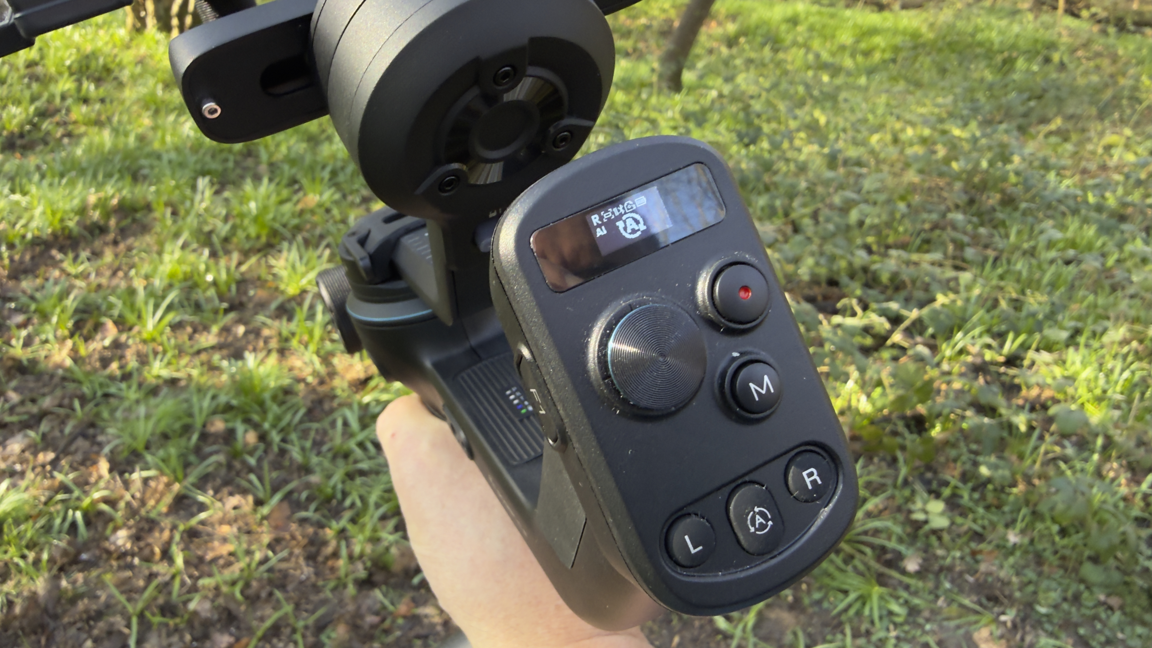 Close-up of a gimbal control handle with screen, joystick, and mode buttons
