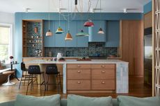 a blue kitchen with colorful pendant lighting and a tile blue and wood island