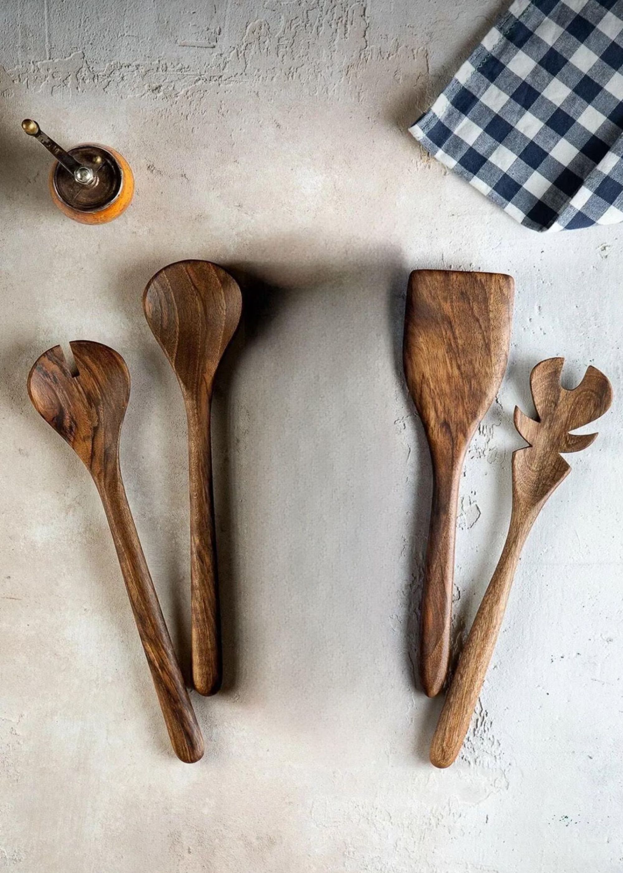 Wooden utensils on a kitchen countertop with a cloth on the side