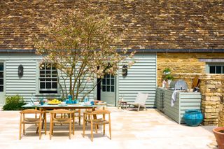 outdoor kitchen ideas: duck-egg coloured kitchen with small tree on patio