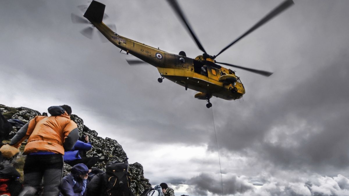 A rescue helicopter hovers above stranded hikers on a mountain