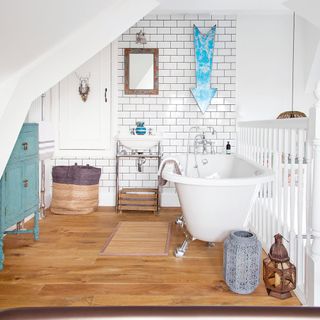 bathroom with white bathtub white tiles and wooden flooring