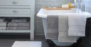 grey bathrooom with freestanding bath shown with a selection of soft fluffy towels