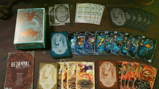 Game components for Betrayal Deck of Lost Souls laid out on a table. The cards feature horror-inspired illustrations and ornate gnarled trees.