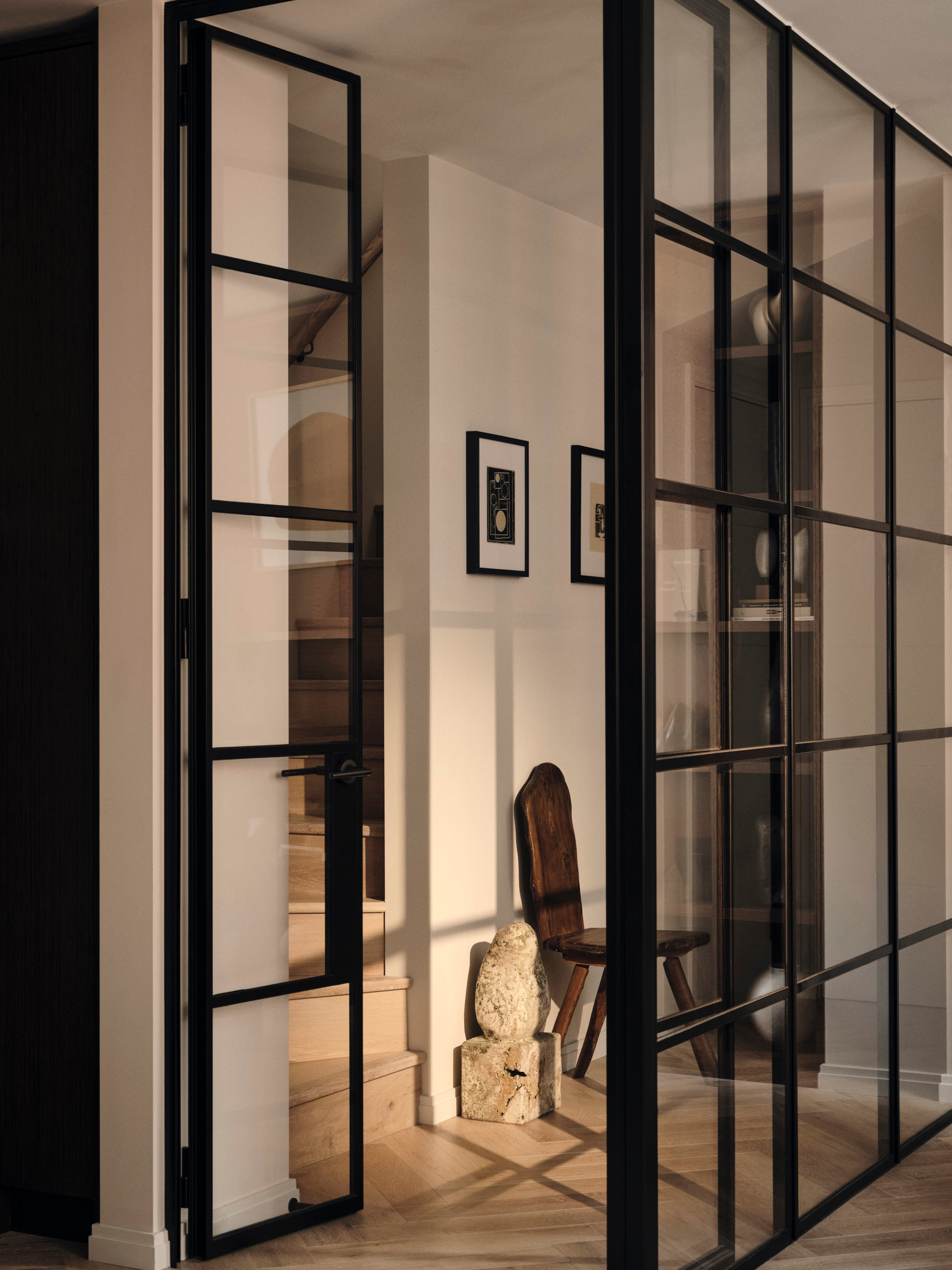 Shot of hallway with curved wood staircase and black-framed Crittall-style doors