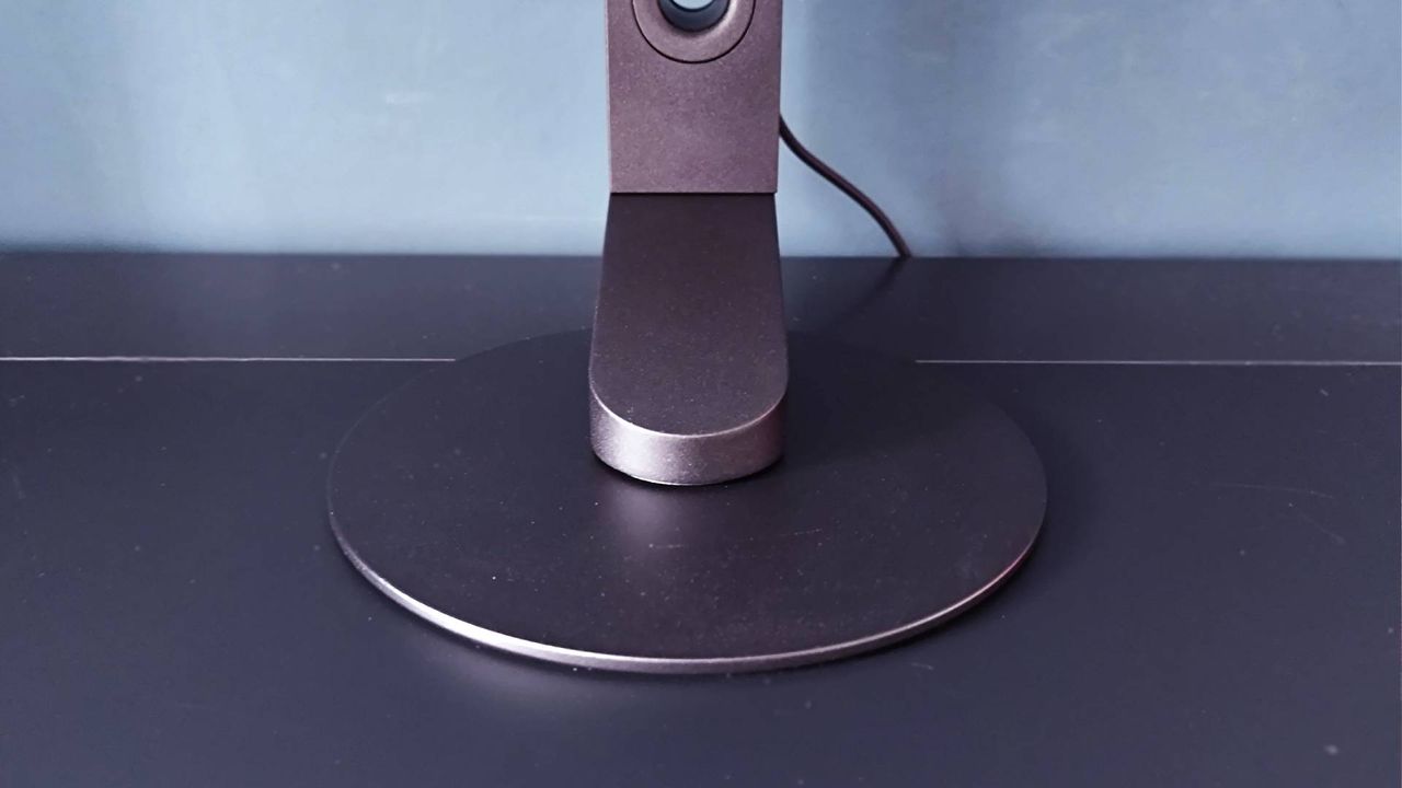 Close up of circular Sony Inzone M10S II stand on black desk.