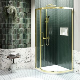 Bathroom with green wall tiles and white floor tiles and a gold framed corner shower enclosure