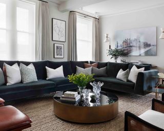 neutral living room with dark gray sectional, jute carpet and round coffee table