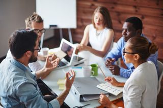 A group of employees discuss strategy around a table