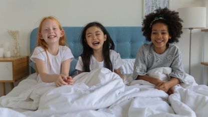 Three young girls sat in bed laughing