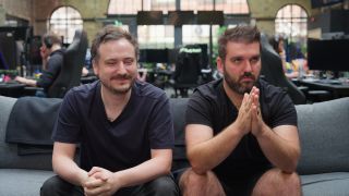 Two Wardogs developers sitting on a gray couch