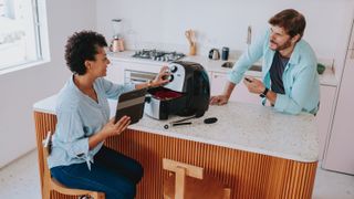 Man and woman setting up new air fryer in kitchen