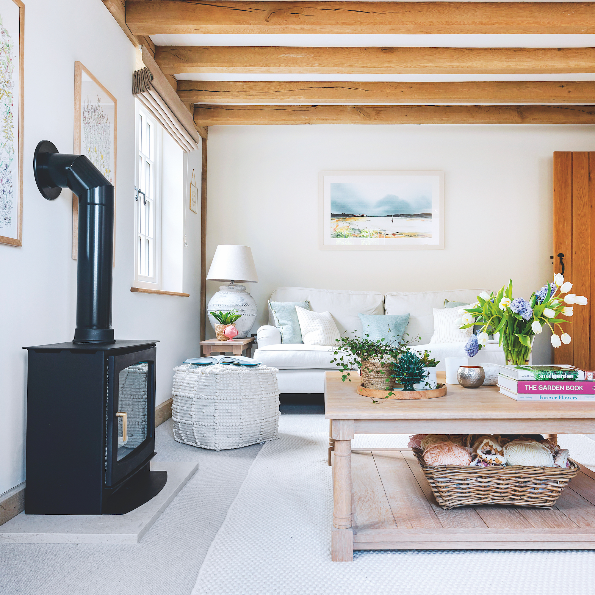 sitting room with oak beam ceiling, large black woodburning stove and coffee table