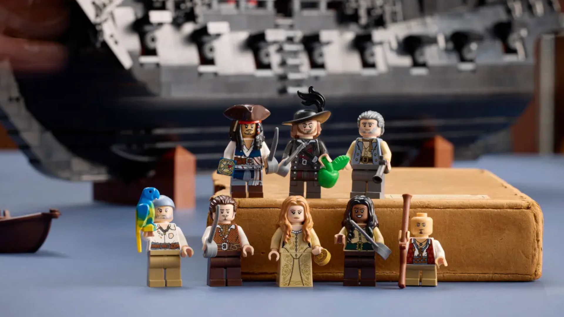 Lego Pirates of the Caribbean minifigures laid out on a blue surface, with some on a book