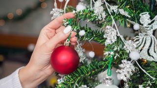 Woman hanging a bauble on a Christmas tree