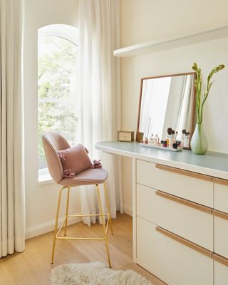 A bedroom dresser with pink chair and make up