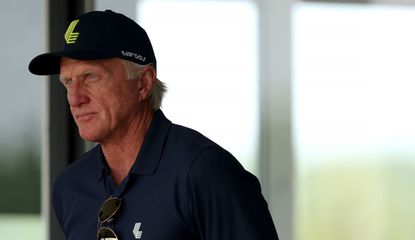 Greg Norman looks on from a suite by the 18th