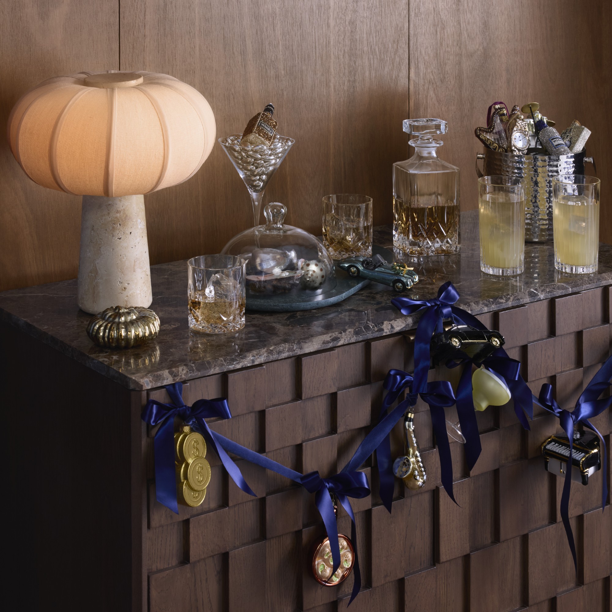 A home bar with a table lamp decorated for the festive season with baubles from The Connoisseur theme at John Lewis