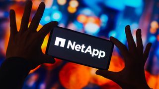 NetApp logo appearing on a smartphone background set against a multicoloured cityscape, out of focus, with lots of bokeh