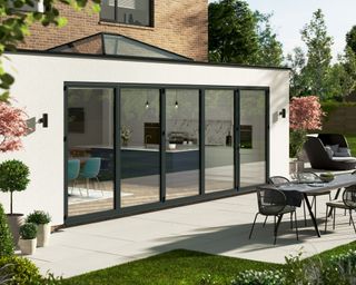 A modern home with Korniche bi-fold doors (Outside perspective with outdoor dining furniture)