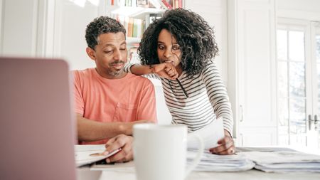 An older couple work on financial planning together at their kitchen table.