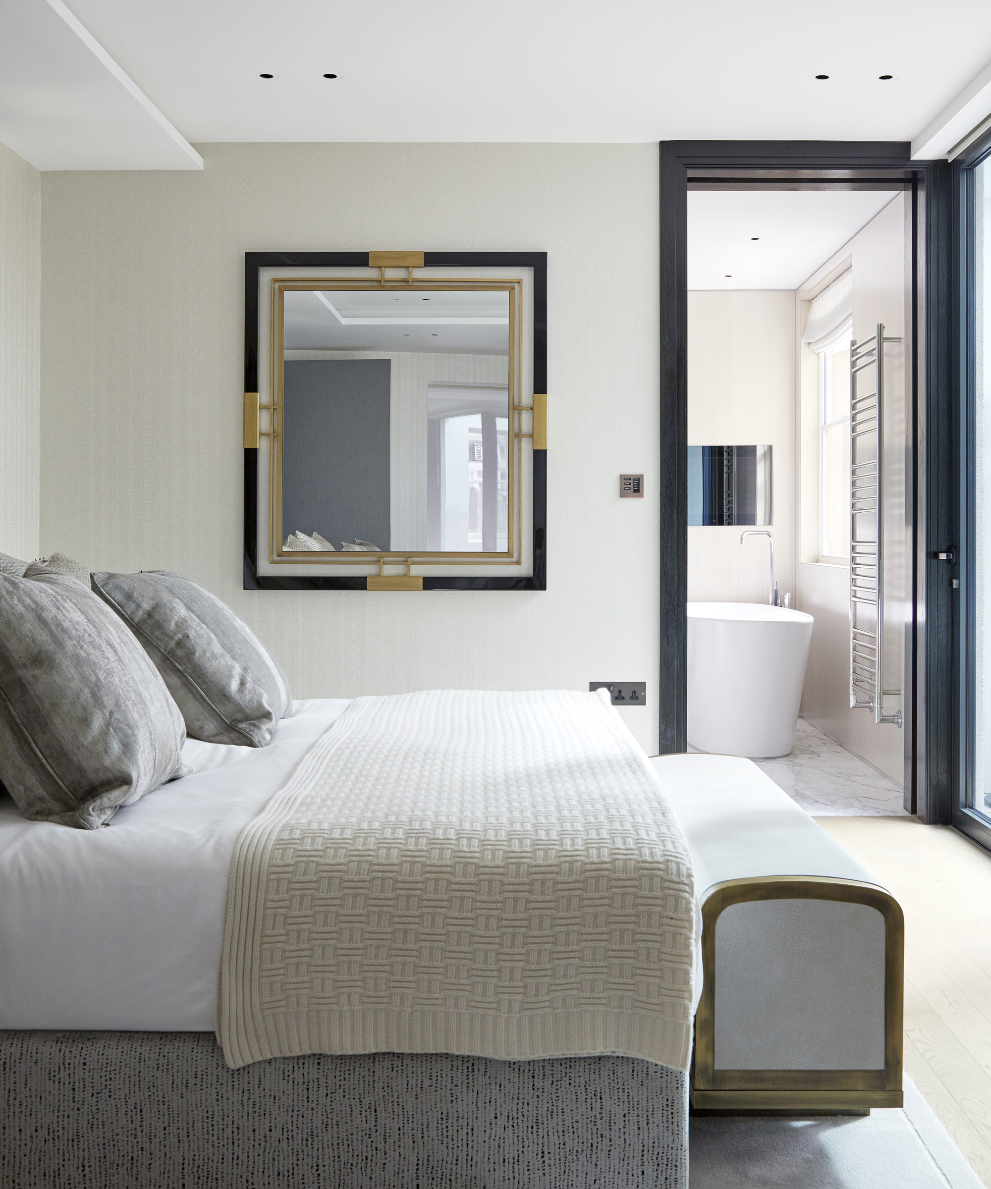A white bedroom idea with dark blue painted woodwork and black and gold geometric mirror
