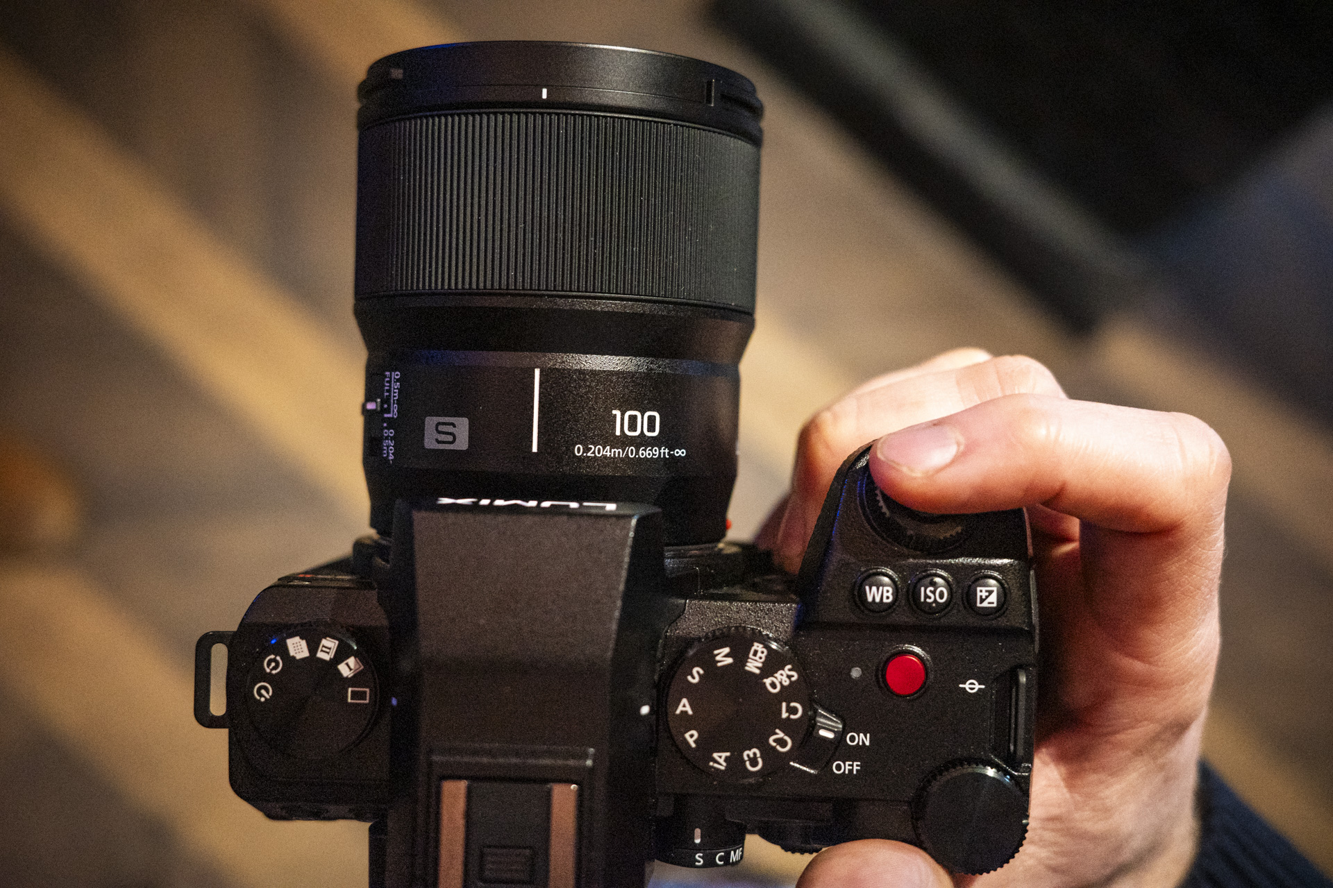 Panasonic Lumix S 100mm F2.8 Macro lens attached to a Lumix S5 II in the hand