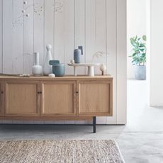 Polished concrete flooring with wooden sideboard and neutral textured rug