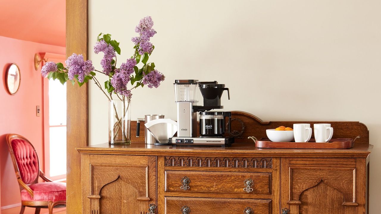 Moccamaster KBGV Select in silver on a wooden cabinet with flowers and filter paper around it