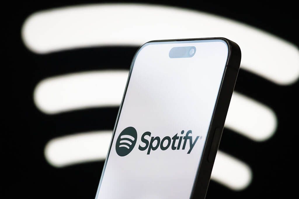 Spotify logo in black on a phone screen against a black background with a white Spotify logo