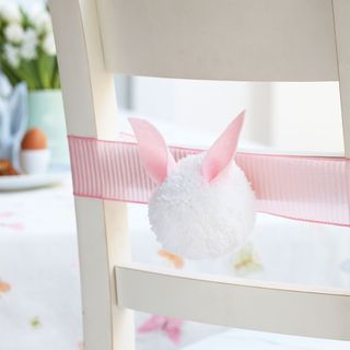 white dining chair decorated with pom pom bunny tail
