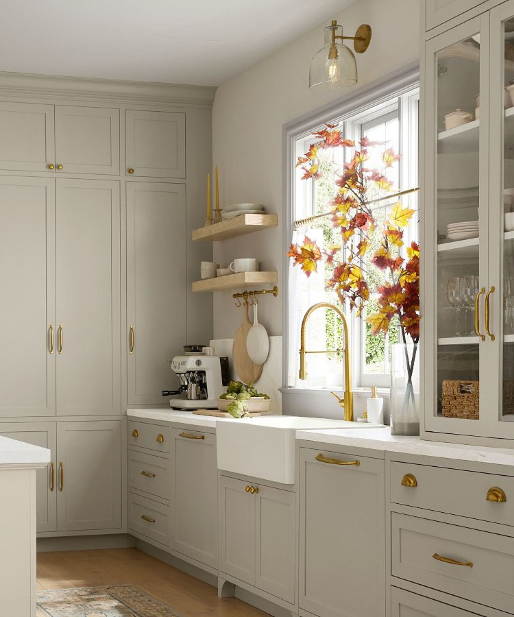 A Pottery Barn kitchen with warm gray cabinets, brass hardware, and white countertops