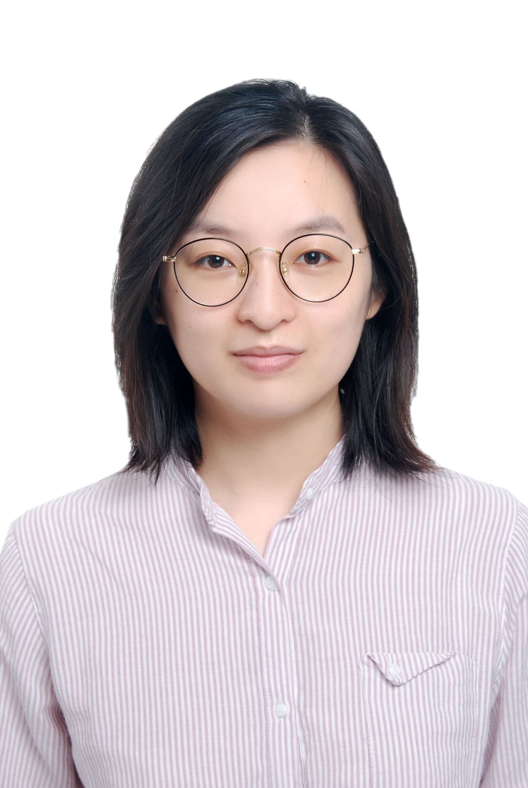 A woman with black hair a striped shirt and round glasses with a plain white backdrop