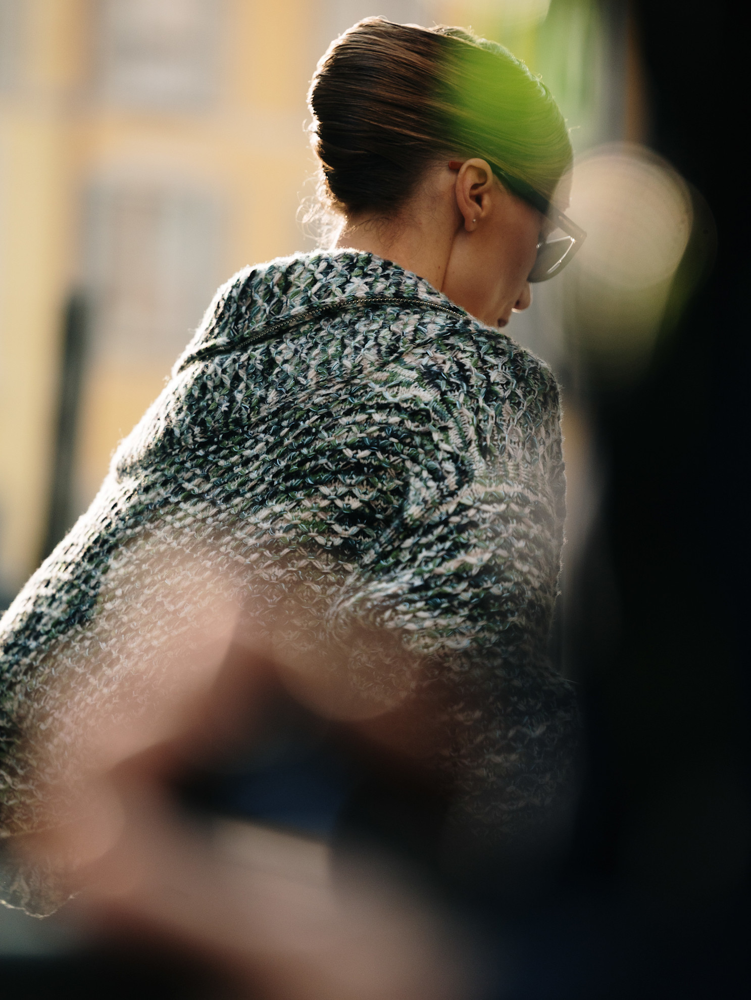 a woman shown from the back in a black and white coat with a French twist