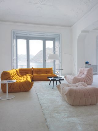 A living room with white walls and a bright yellow sofa