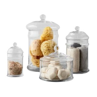 Various sizes of glass canisters with bathroom products inside