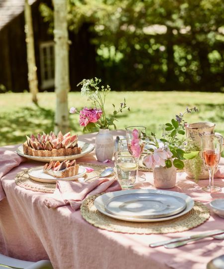 table outdoors with soft pink linen, plates and glasses of rose wine, and a fig tart