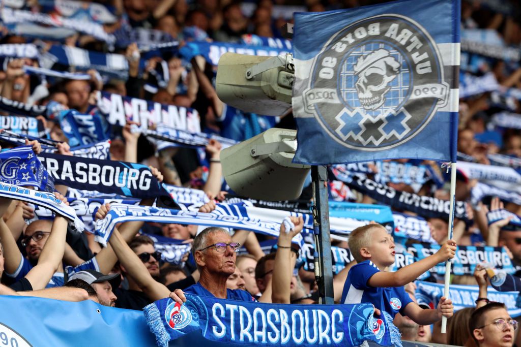 Strasbourg&#039;s supporters holding up scarves and a flag attend the French L1 football match between RC Strasbourg Alsace and Toulouse FC at Stade de la Meinau in Strasbourg, eastern France on August 27, 2023.