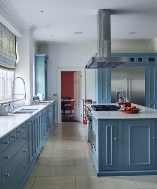 blue farmhouse kitchen island and run of units with hood over hob