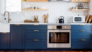 Contemporary dark blue shaker style kitchen with white worktop and metro tiles