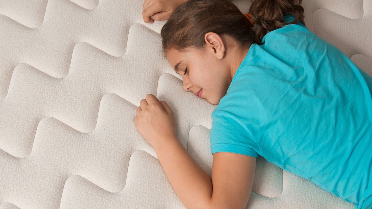 Girl lying on her front smiling on a new mattress