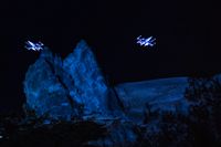 two illuminated spaceships rise above a mock mountain range