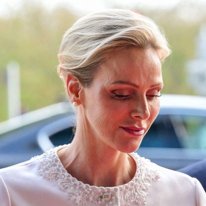 Princess charlene wearing a white jacket and looking down