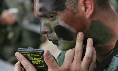 A U.S. Air Force airman applies camouflage makeup before an urban training session in 2006